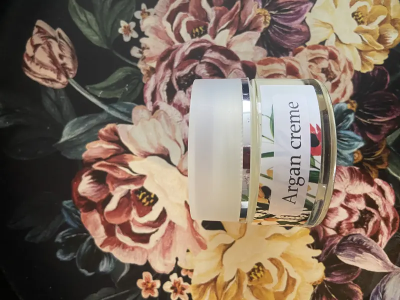 Pot arganchrème op een bloemenachtergrond